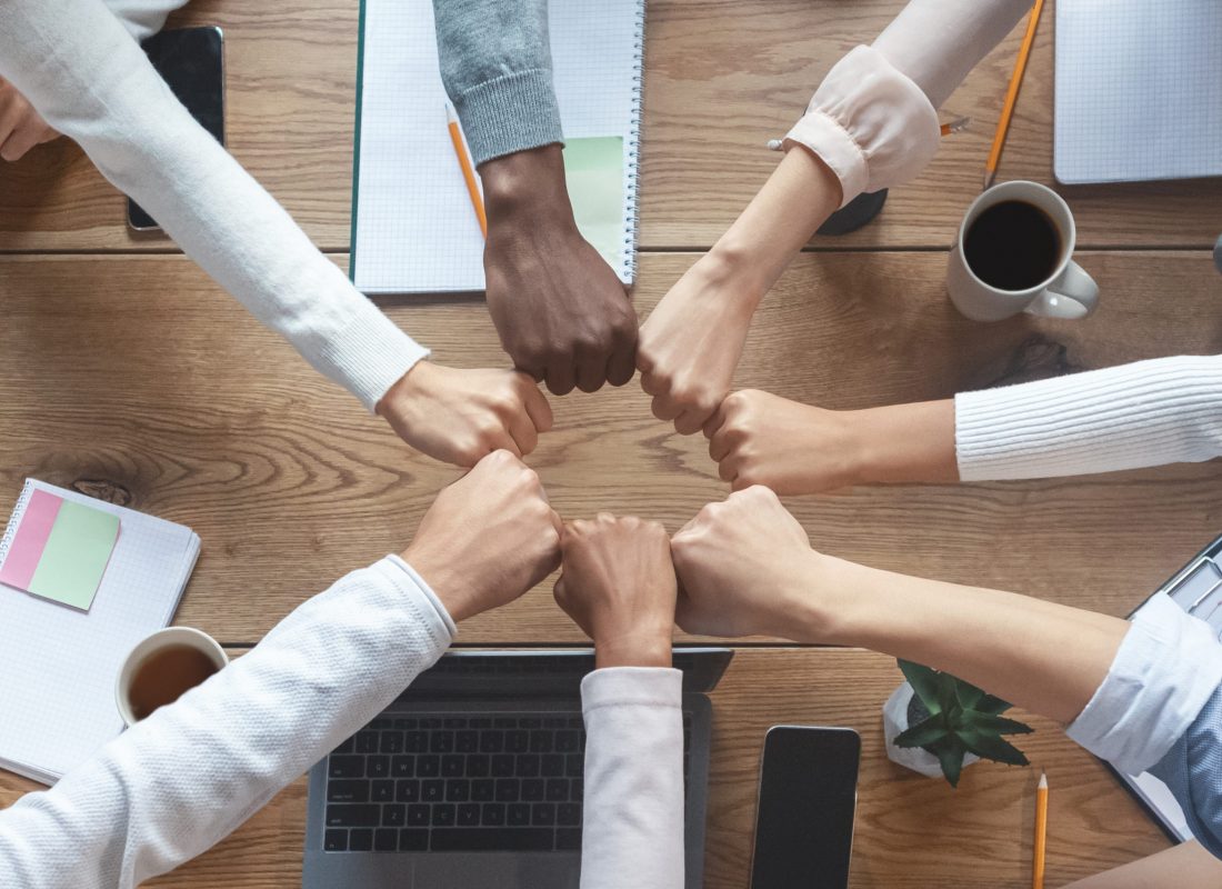 Top view of international group of business people putting fists in circle in cooperation, cropped